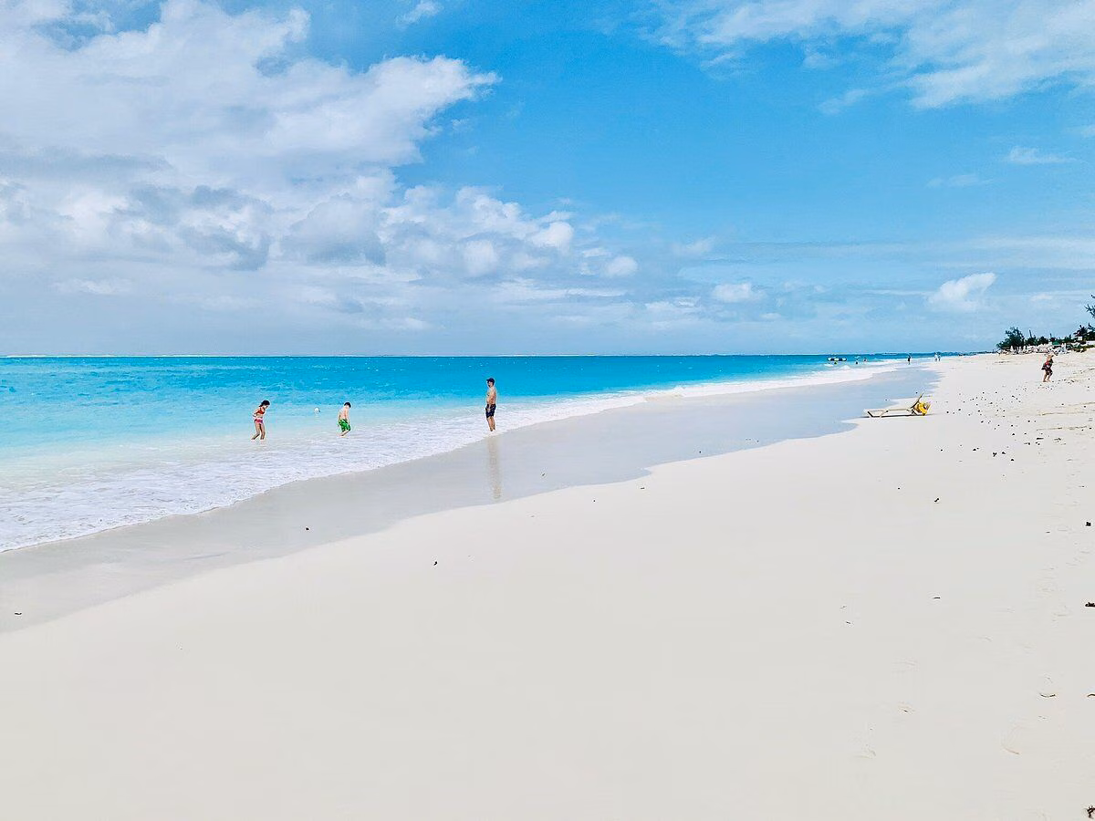 Two figures walking along the shore at Grace Bay