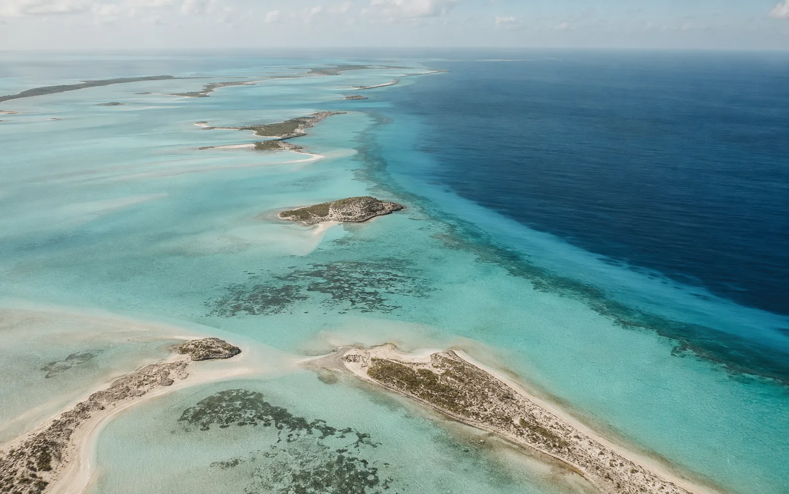 Aerial view of the Turks and Caicos cays, turquoise shallows meeting deep ocean blue along the reef line